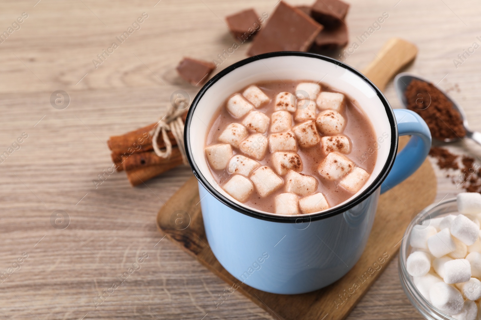 Photo of Cup of aromatic hot chocolate with marshmallows, and cocoa powder on wooden table, closeup. Space for text