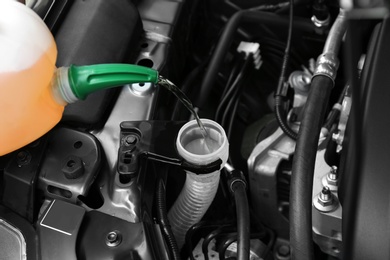 Photo of Pouring liquid from plastic canister into car washer fluid reservoir, closeup