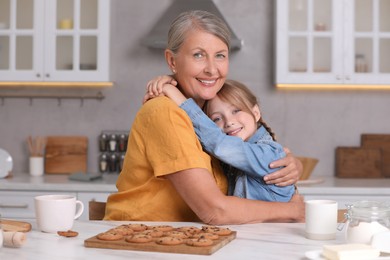 Happy grandmother hugging her granddaughter in kitchen
