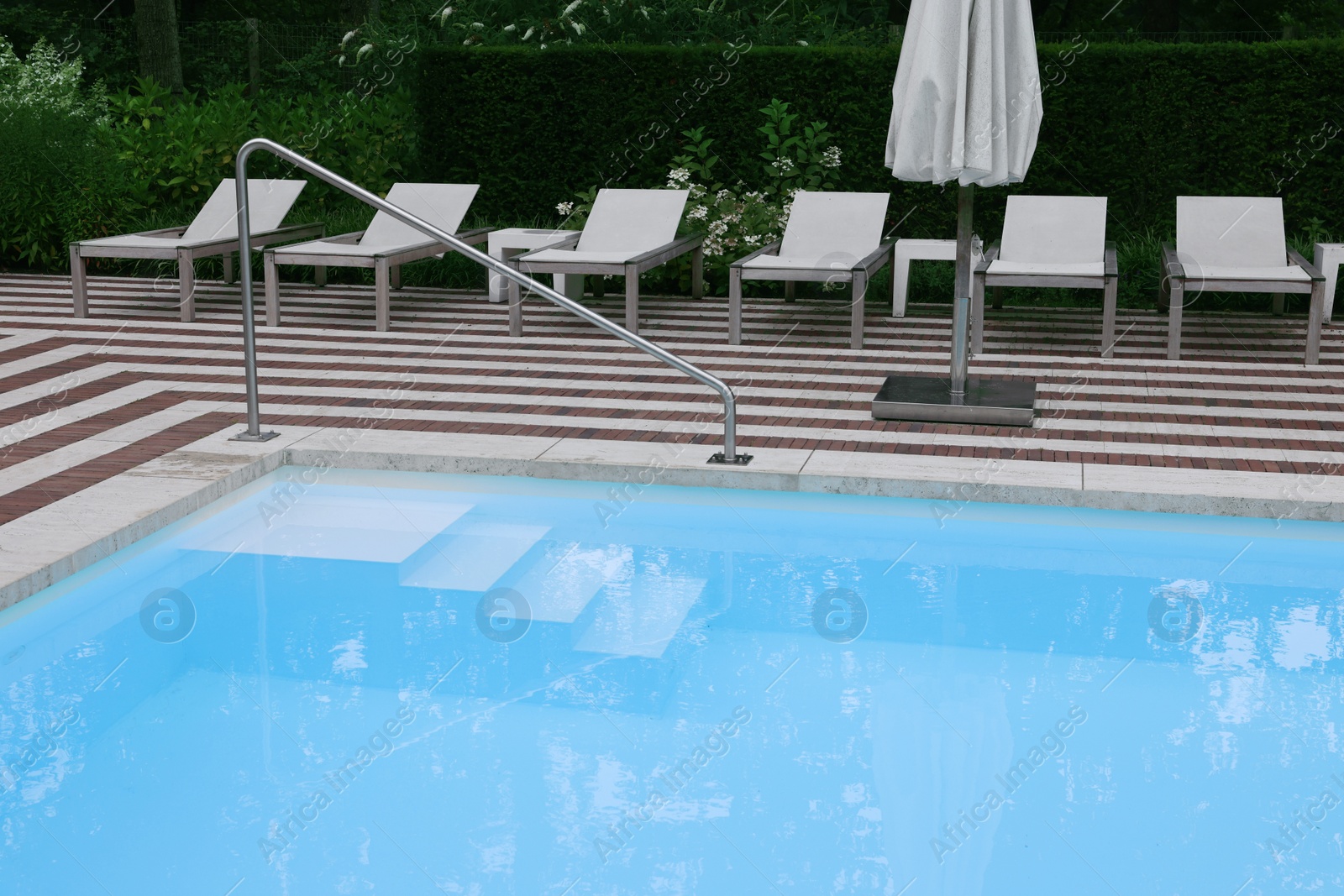 Photo of Many sunbeds and umbrella near outdoor swimming pool