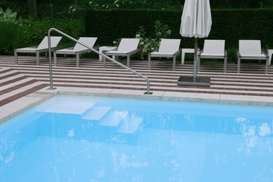 Photo of Many sunbeds and umbrella near outdoor swimming pool