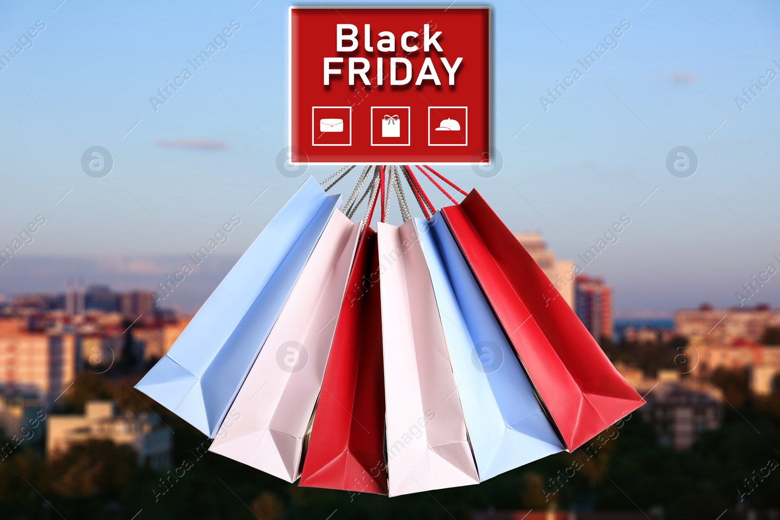 Image of Black Friday. Many shopping bags and blurred cityscape on background