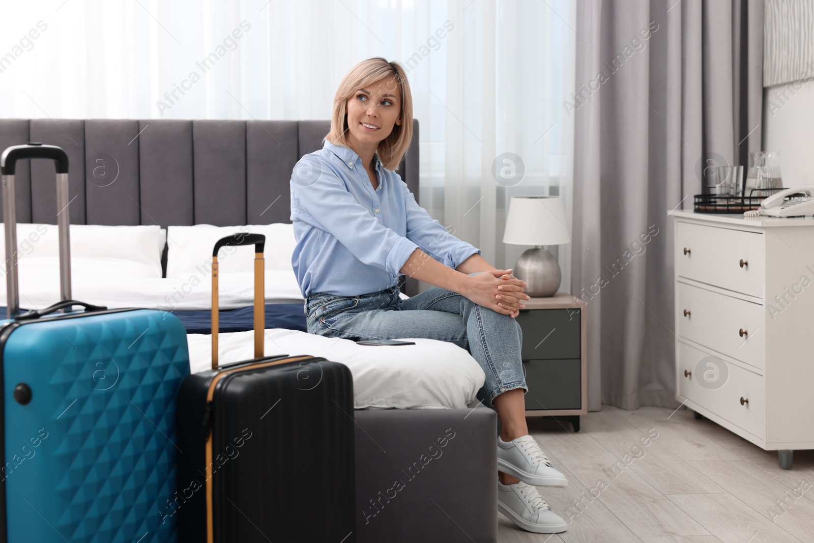 Photo of Smiling guest relaxing on bed in stylish hotel room