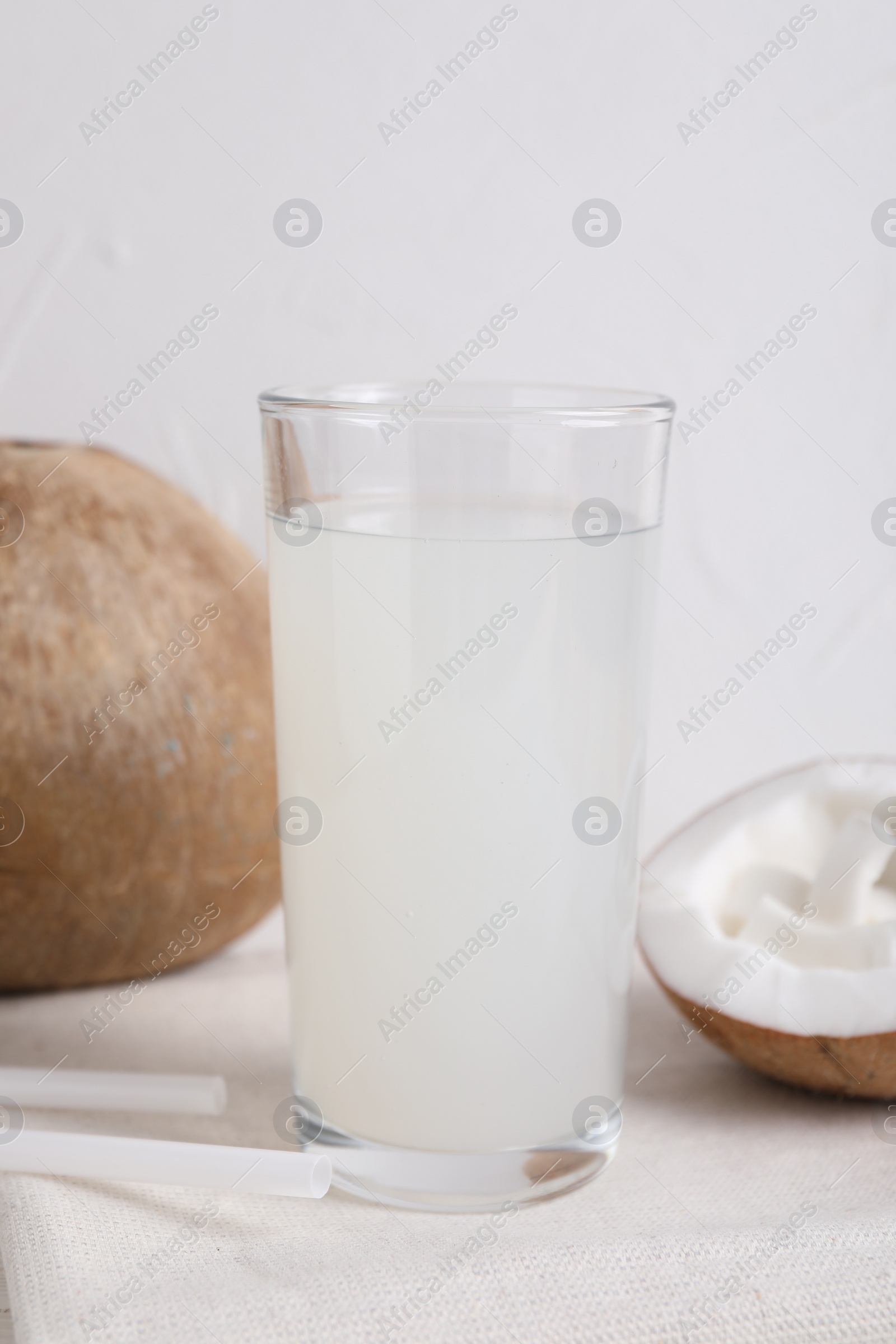 Photo of Glass of coconut water and nuts on white table