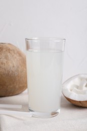 Photo of Glass of coconut water and nuts on white table