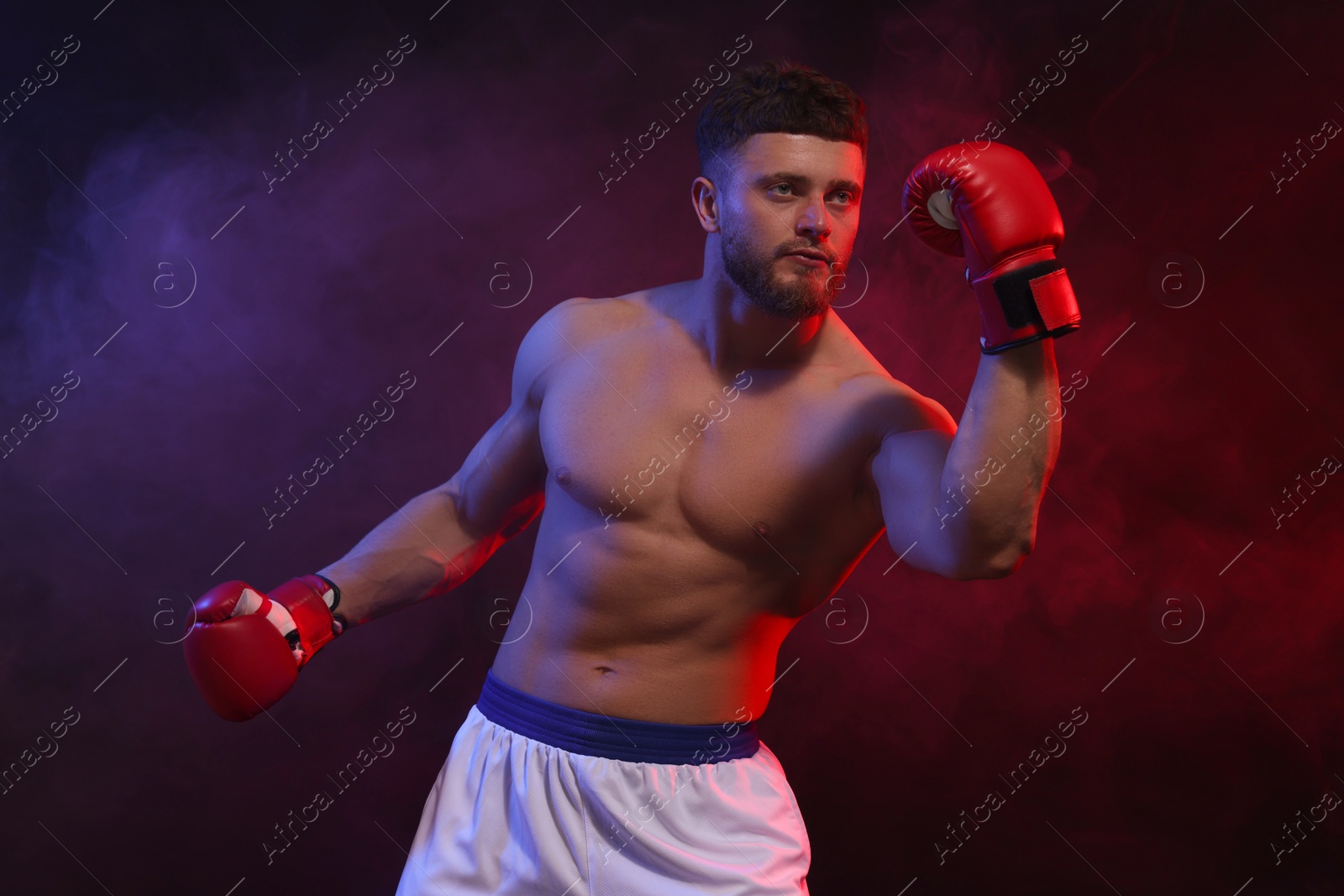 Photo of Man wearing boxing gloves fighting on dark background