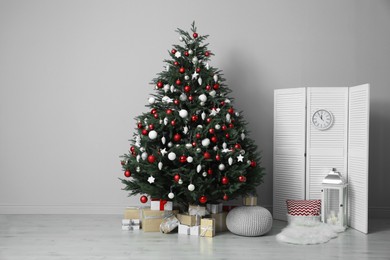 Photo of Beautifully decorated Christmas tree and many gift boxes in room