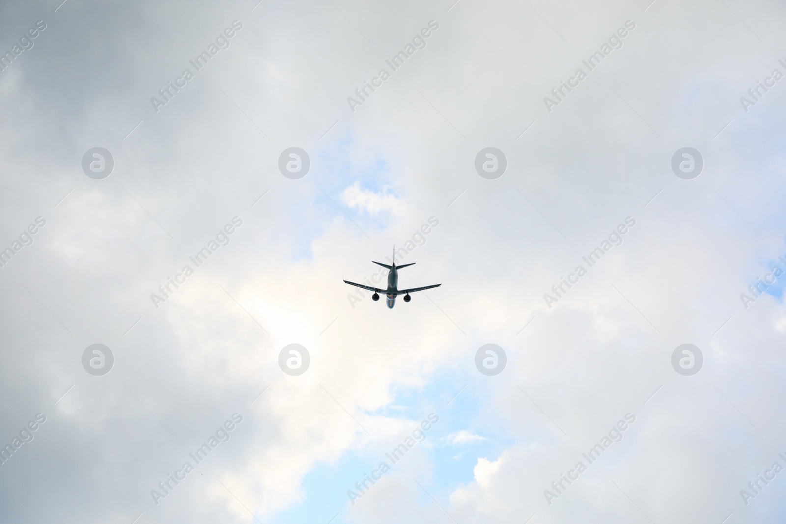 Photo of Modern white airplane flying in cloudy sky, low angle view