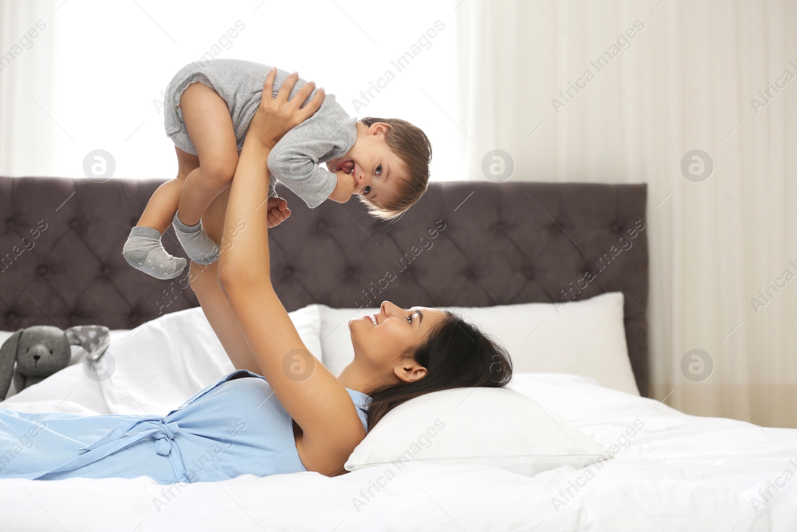 Photo of Young nanny playing with cute little baby in bedroom