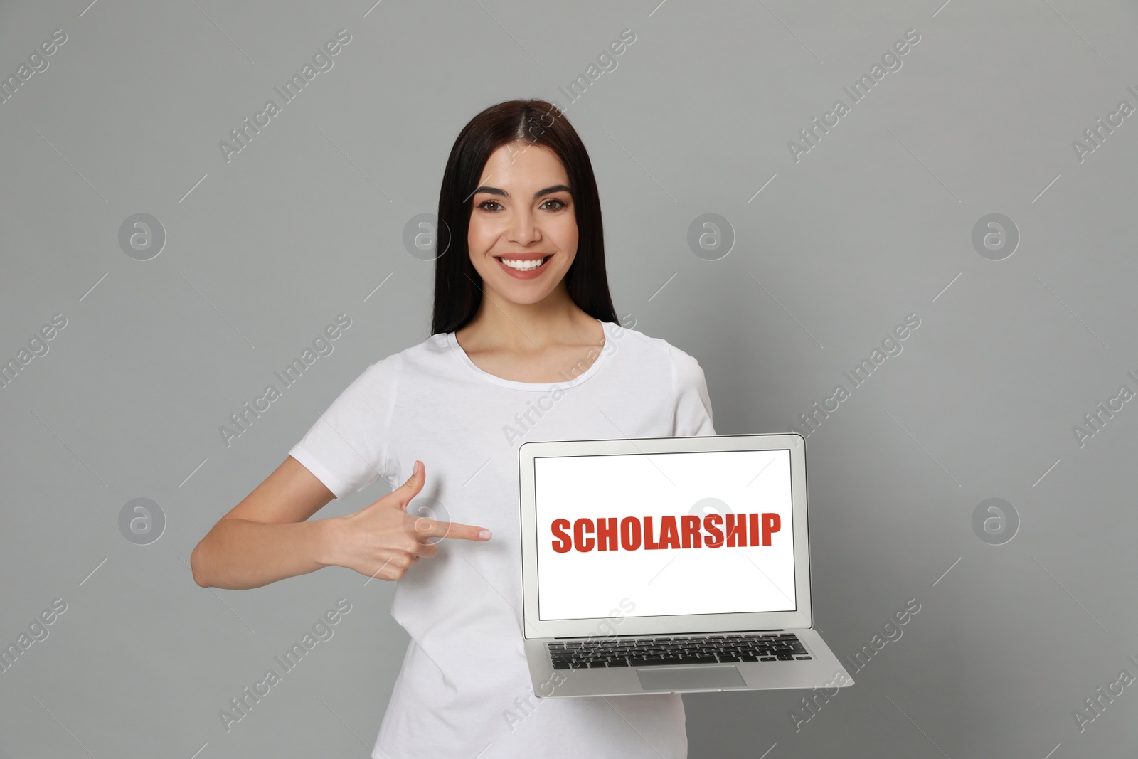 Image of Scholarship concept. Young woman with modern laptop on light grey background