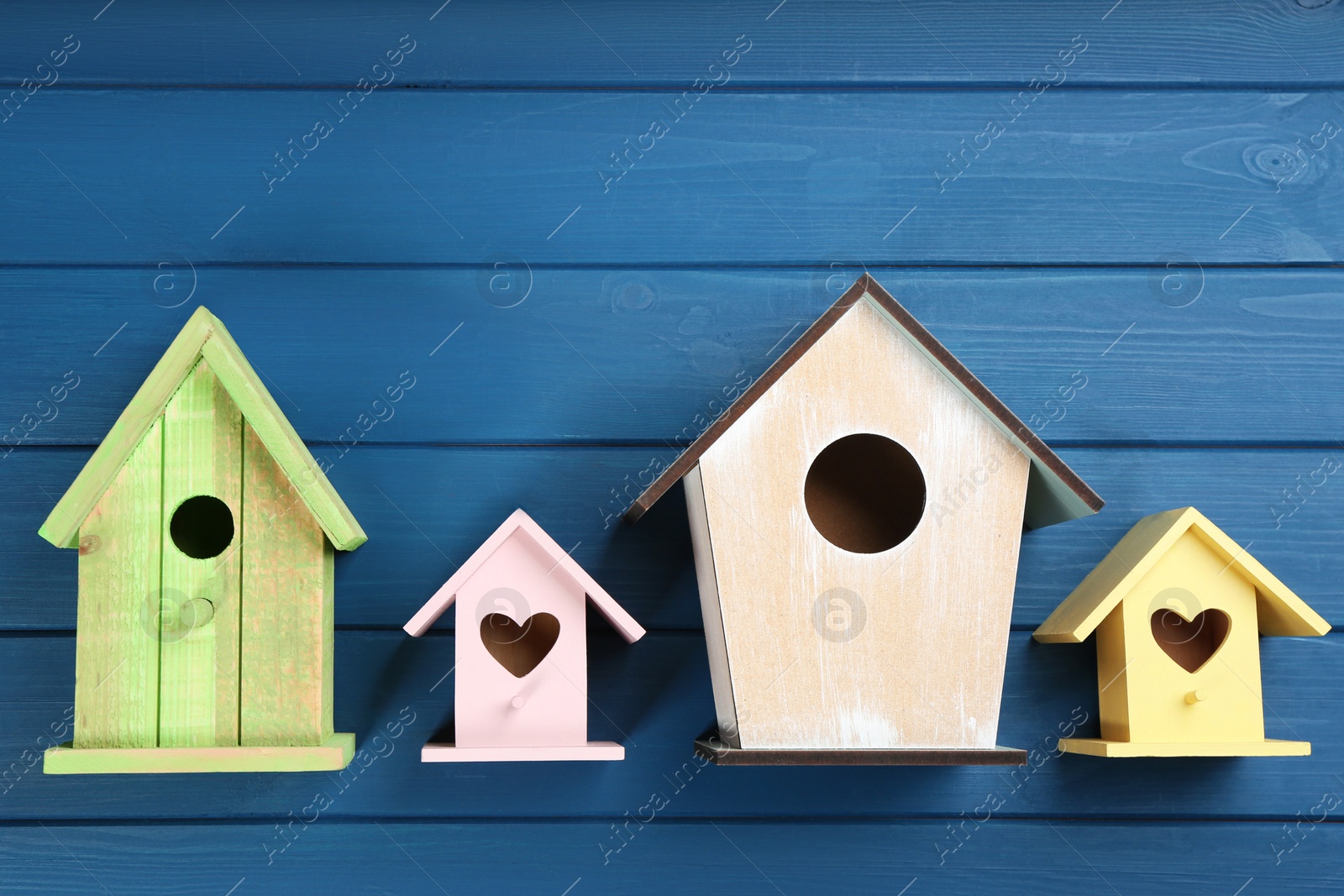 Photo of Beautiful bird houses on blue wooden table, flat lay