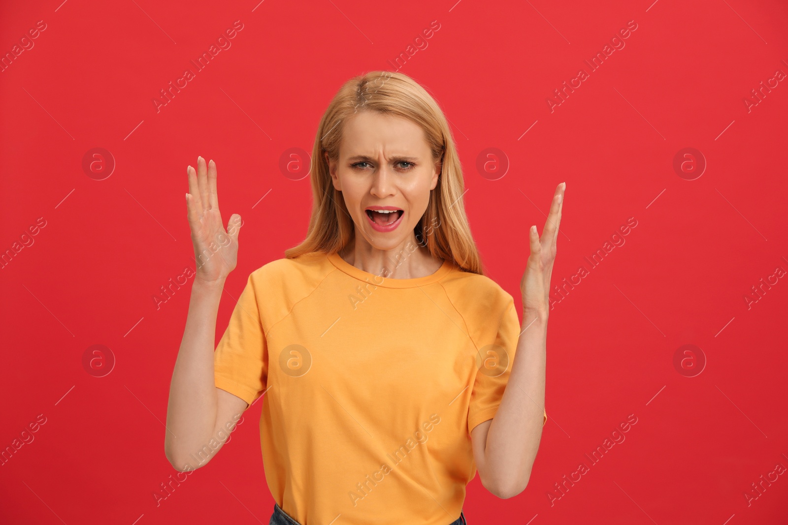 Photo of Angry young woman on red background. Hate concept