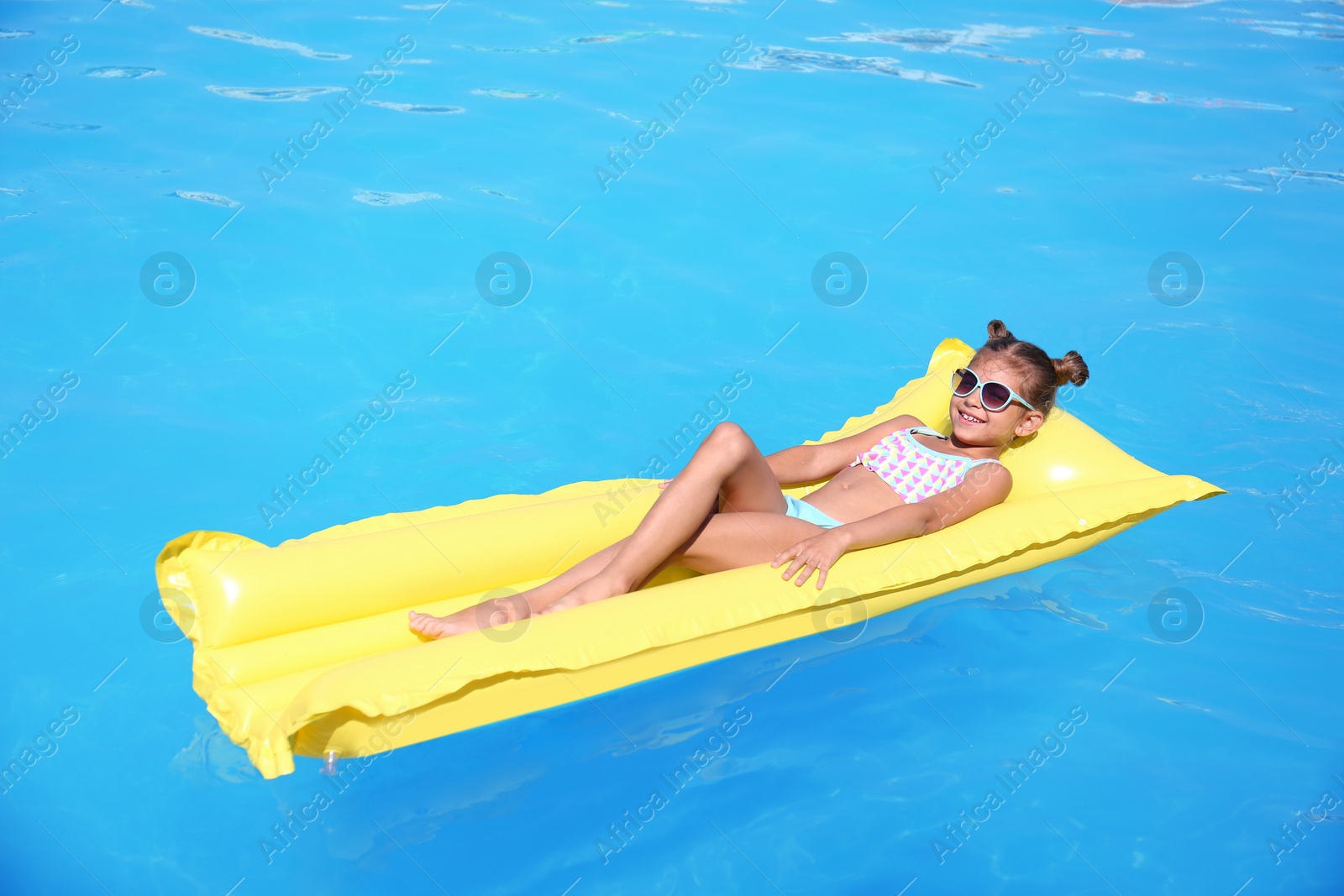 Photo of Cute little girl on inflatable mattress in swimming pool