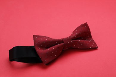 Photo of Stylish burgundy bow tie on red background
