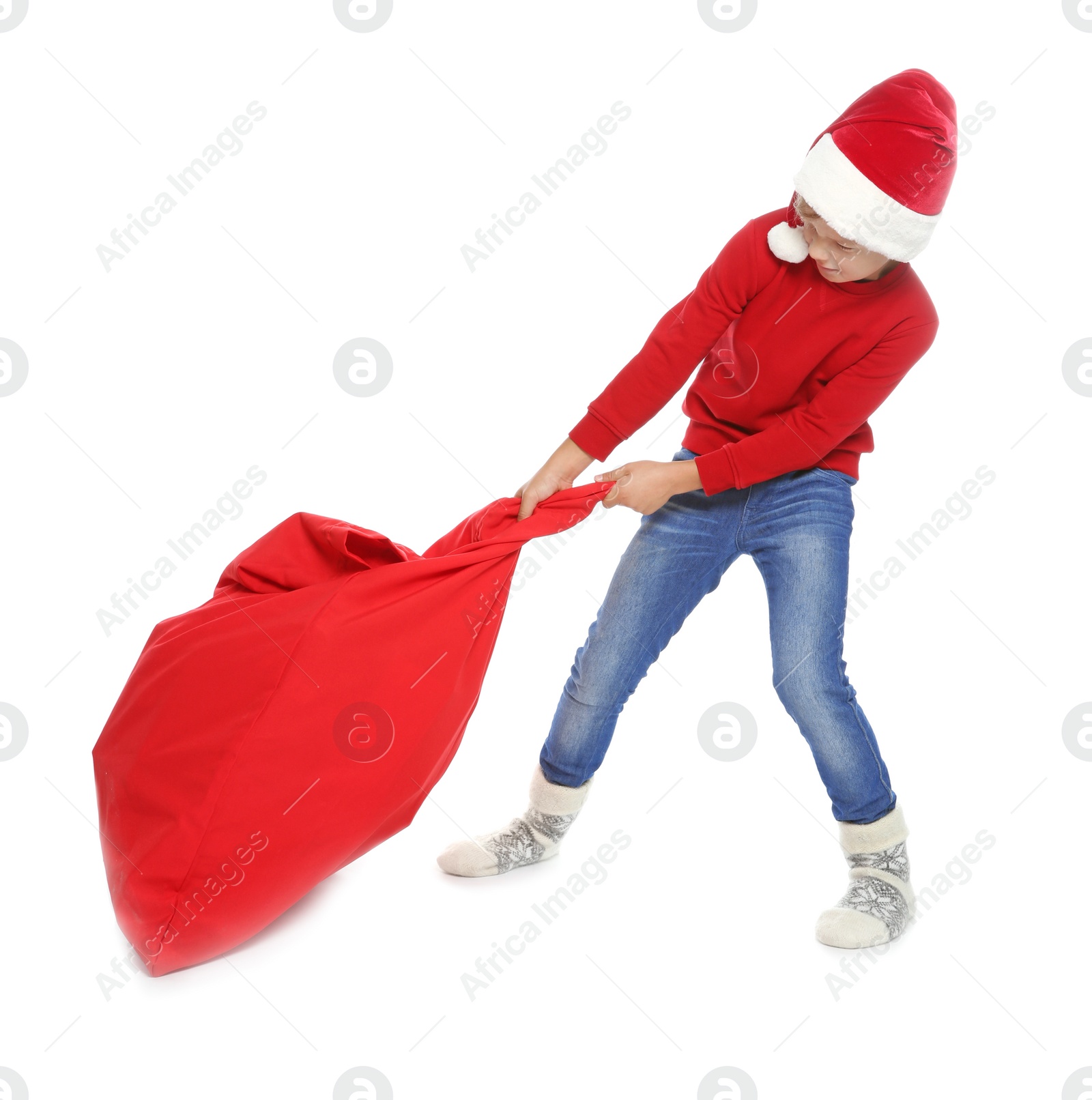 Photo of Cute little child in Santa hat with red Christmas bag on white background