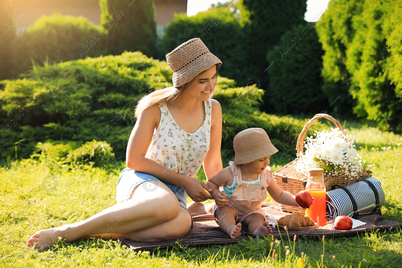 Photo of Mother with her baby daughter having picnic in garden on sunny day