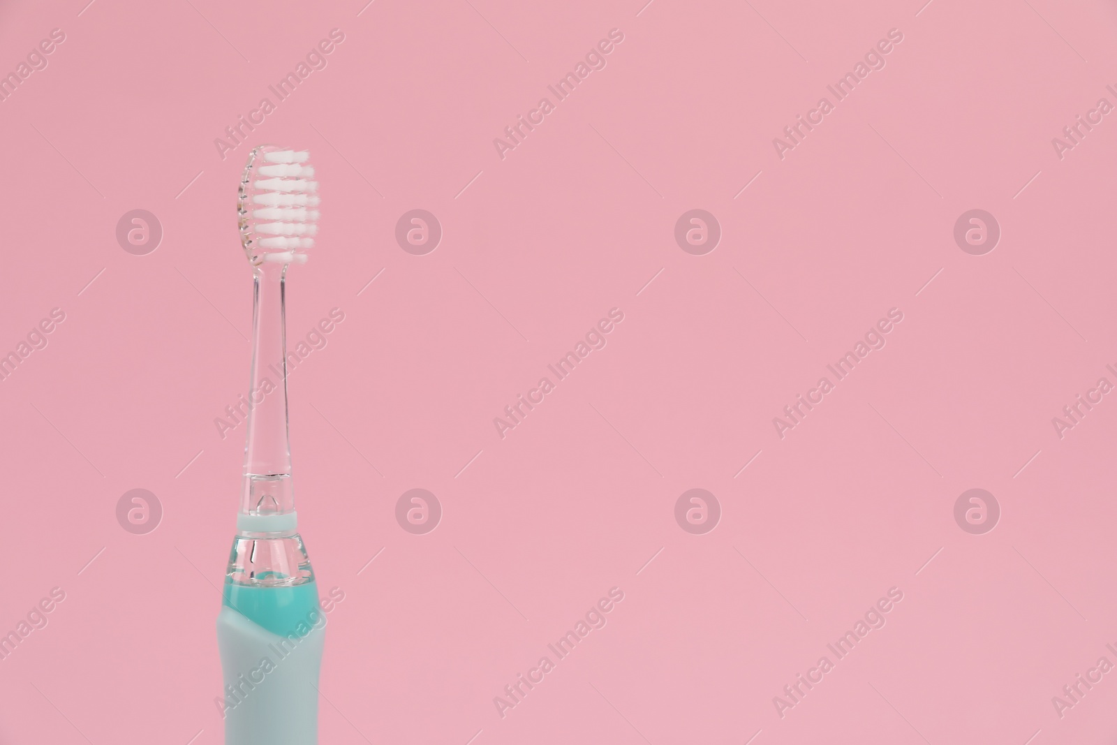 Photo of Electric toothbrush on pink background, space for text