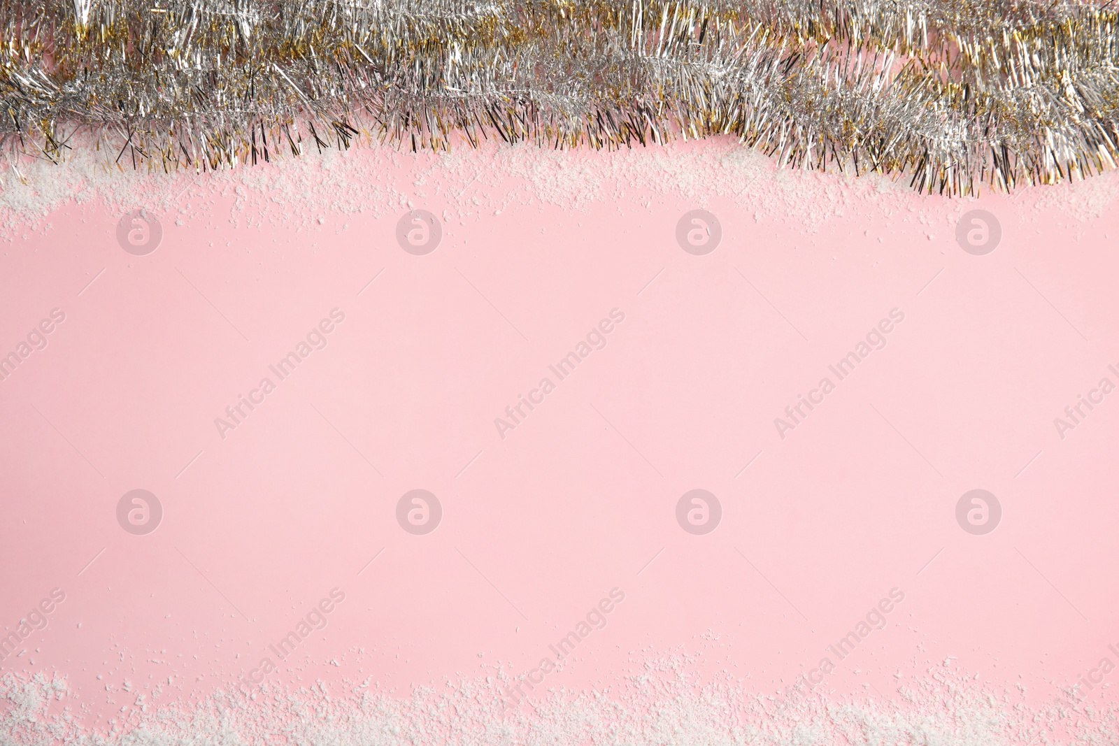 Photo of Shiny tinsel and snow on pink background, top view. Space for text