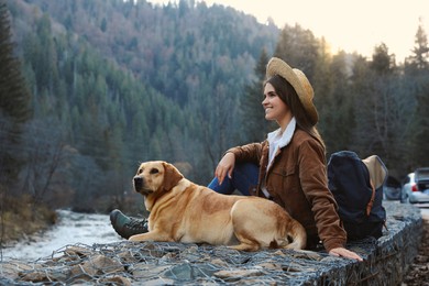 Photo of Happy woman and adorable dog in mountains. Traveling with pet