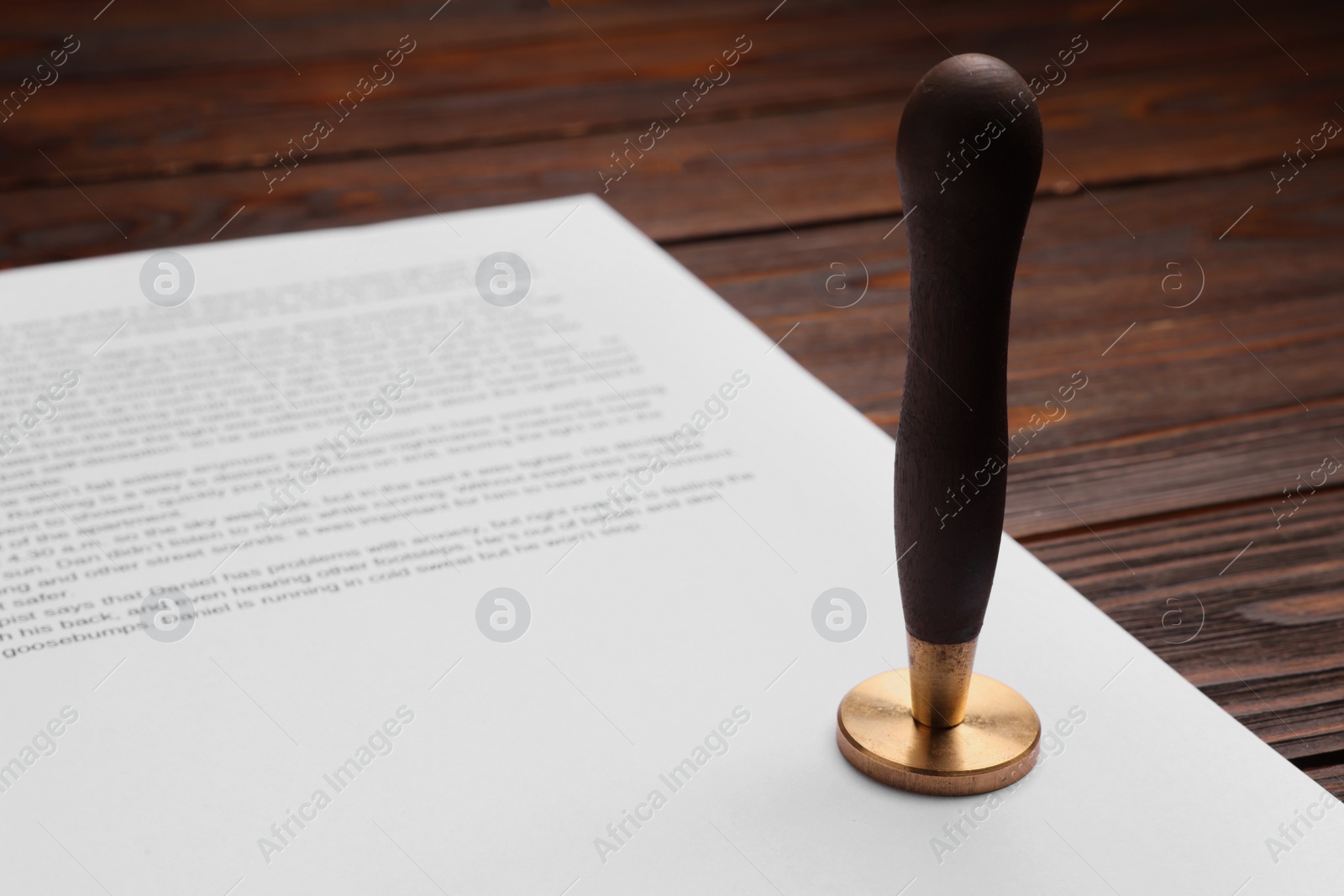 Photo of One stamp tool and document on wooden table, closeup. Space for text