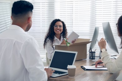 New employee unpacking box while talking with coworkers in office