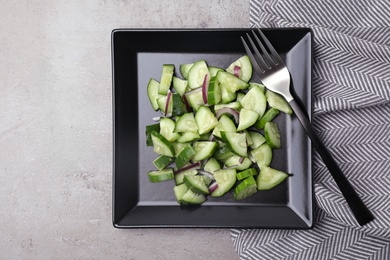 Plate of vegetarian salad with cucumber and onion served on table, flat lay