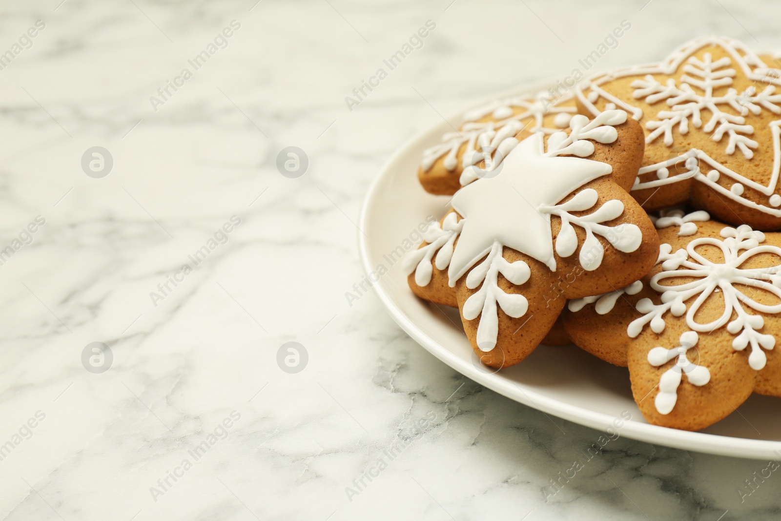 Photo of Tasty star shaped Christmas cookies with icing on white marble table, closeup. Space for text