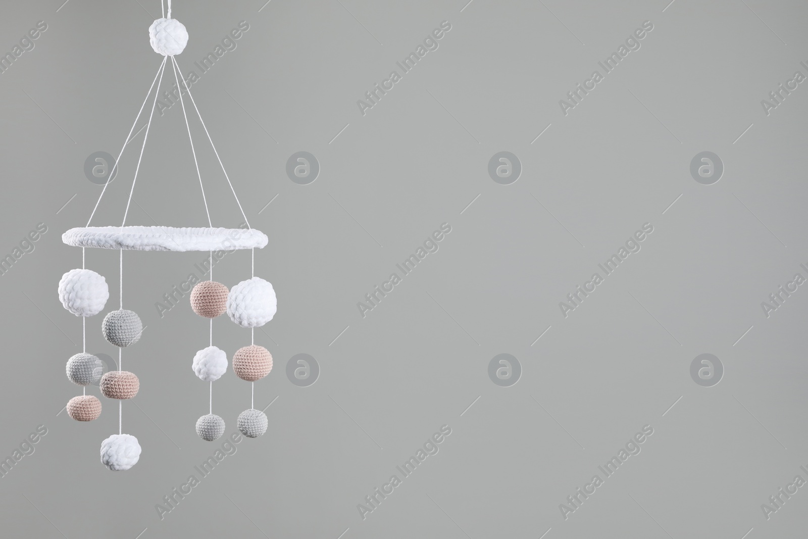 Photo of Cute baby crib mobile on grey background. Space for text