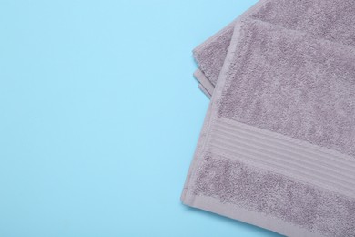 Photo of Violet terry towels on light blue background, top view. Space for text