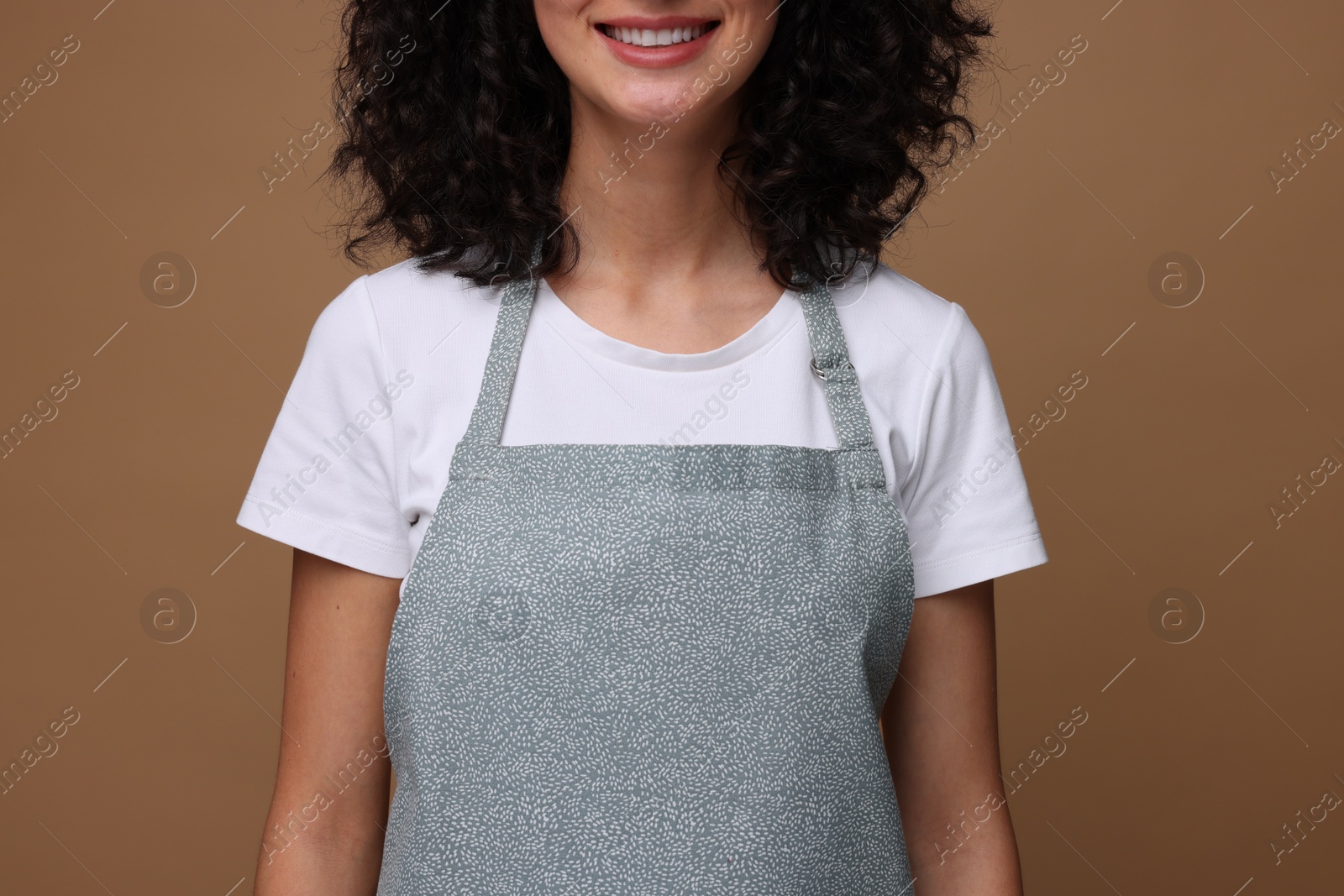 Photo of Woman wearing kitchen apron on brown background, closeup. Mockup for design