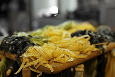 Photo of Natural colorful raw noodles on wooden board, closeup