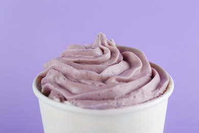 Cup with tasty frozen yogurt on violet background, closeup