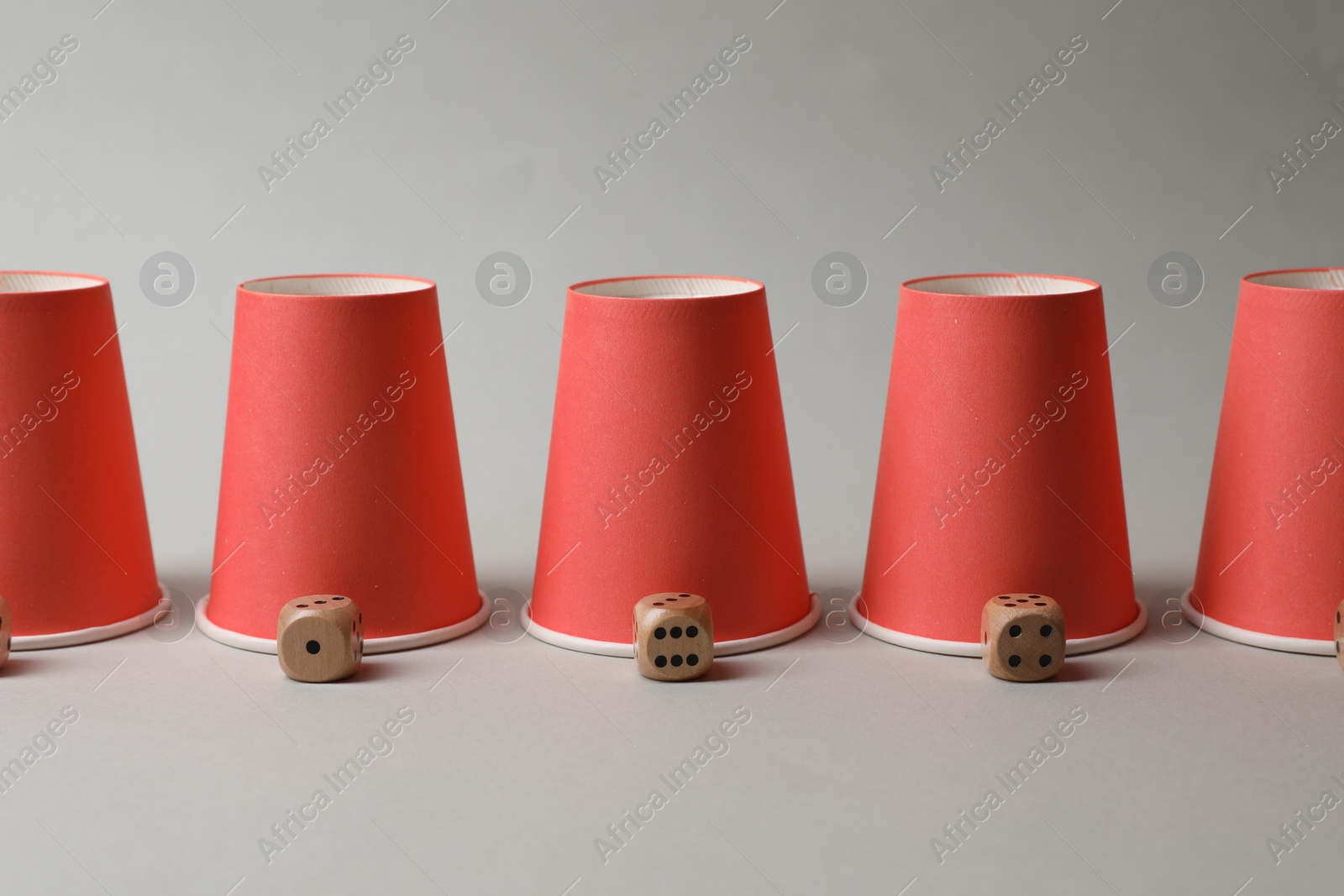 Photo of Red cups and dices on light grey background. Thimblerig game