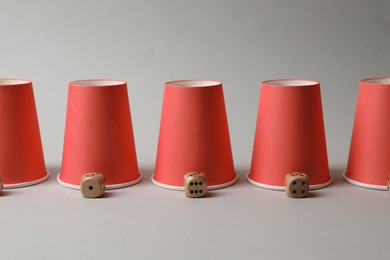 Photo of Red cups and dices on light grey background. Thimblerig game