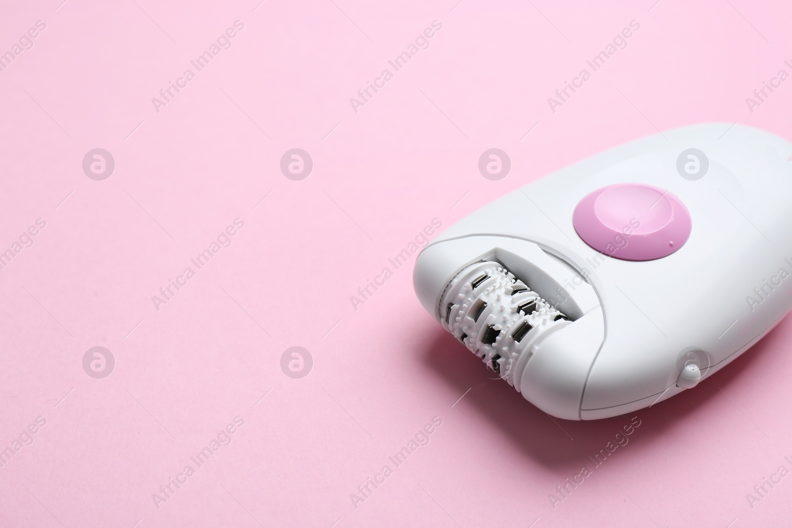 Photo of Modern epilator on pink background. Space for text