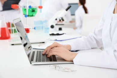 Medical student working with laptop in modern laboratory, closeup
