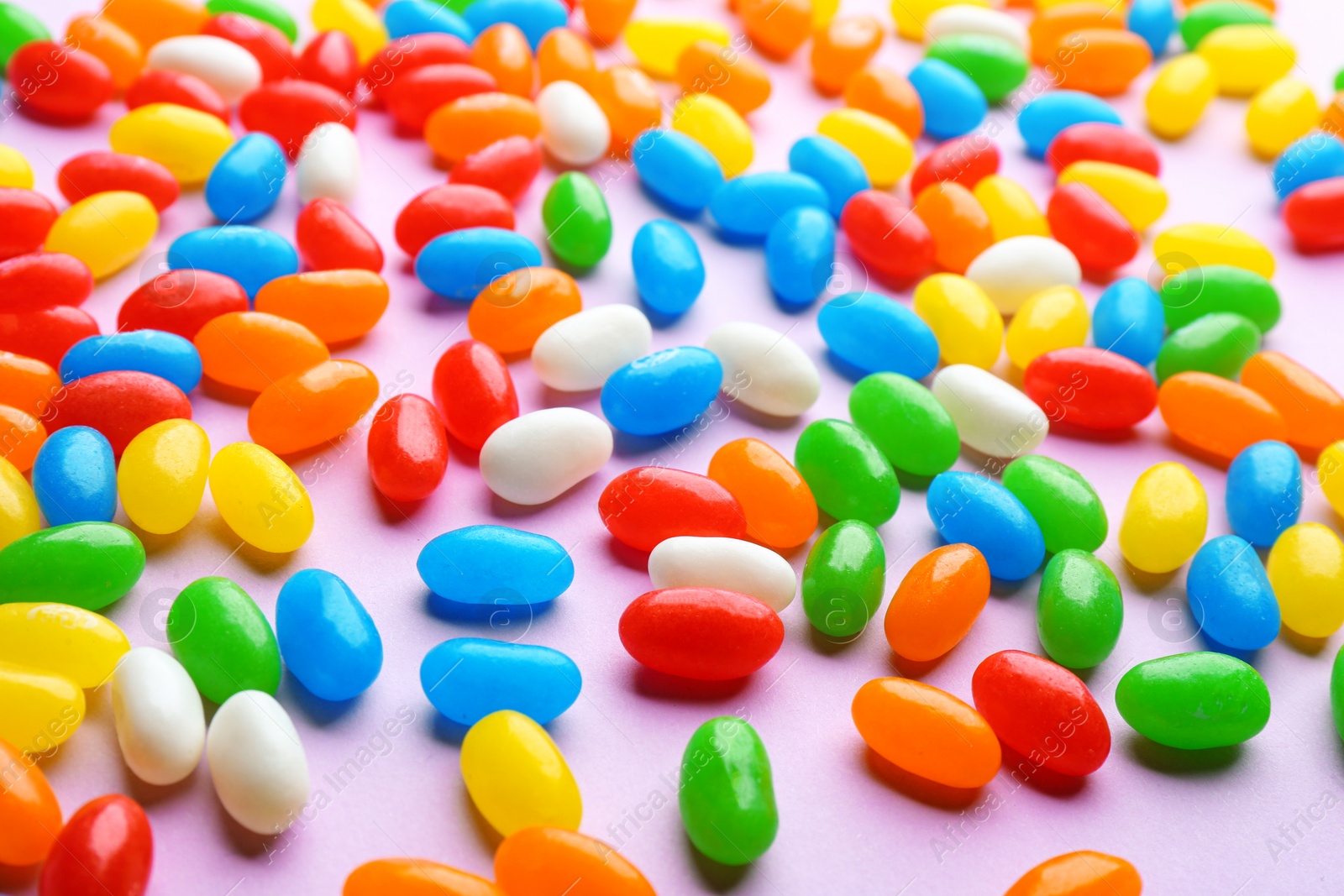 Photo of Colorful sweet jelly beans on lilac background