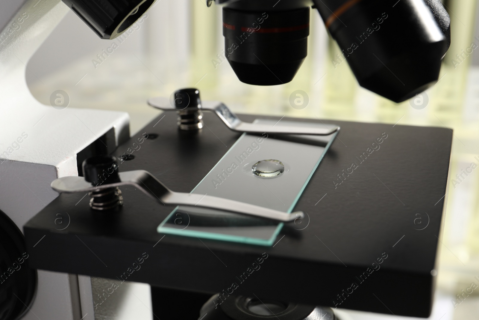 Photo of Microscope with drop of urine on glass slide in laboratory, closeup