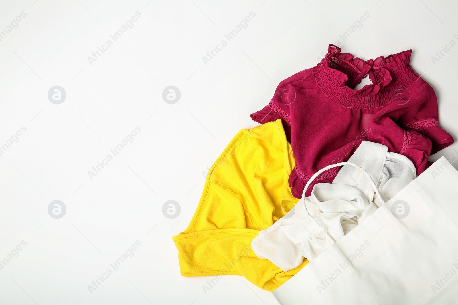 Photo of Stylish flat lay composition with shopping bag and clothing on white background