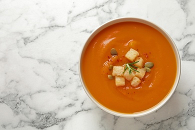 Photo of Bowl of tasty sweet potato soup on marble table, top view. Space for text