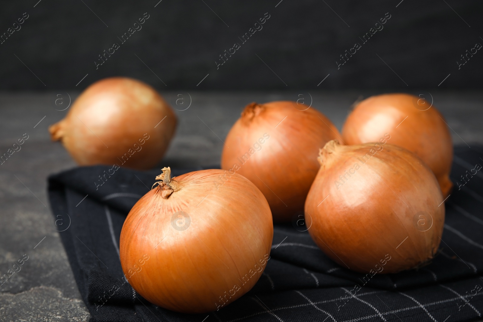 Photo of Black fabric with ripe onions on grey table