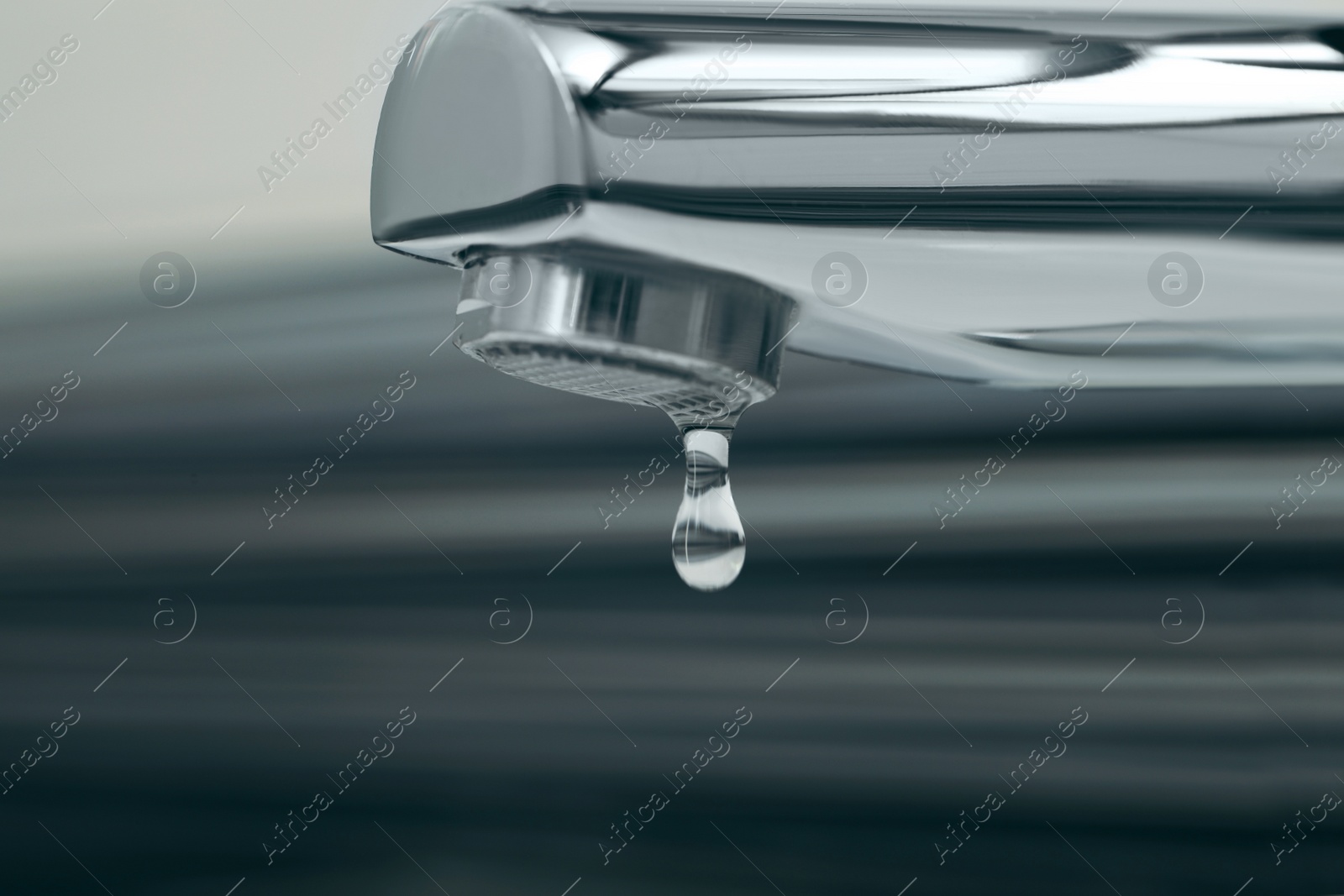 Photo of Water drop falling down from tap on blurred background, closeup