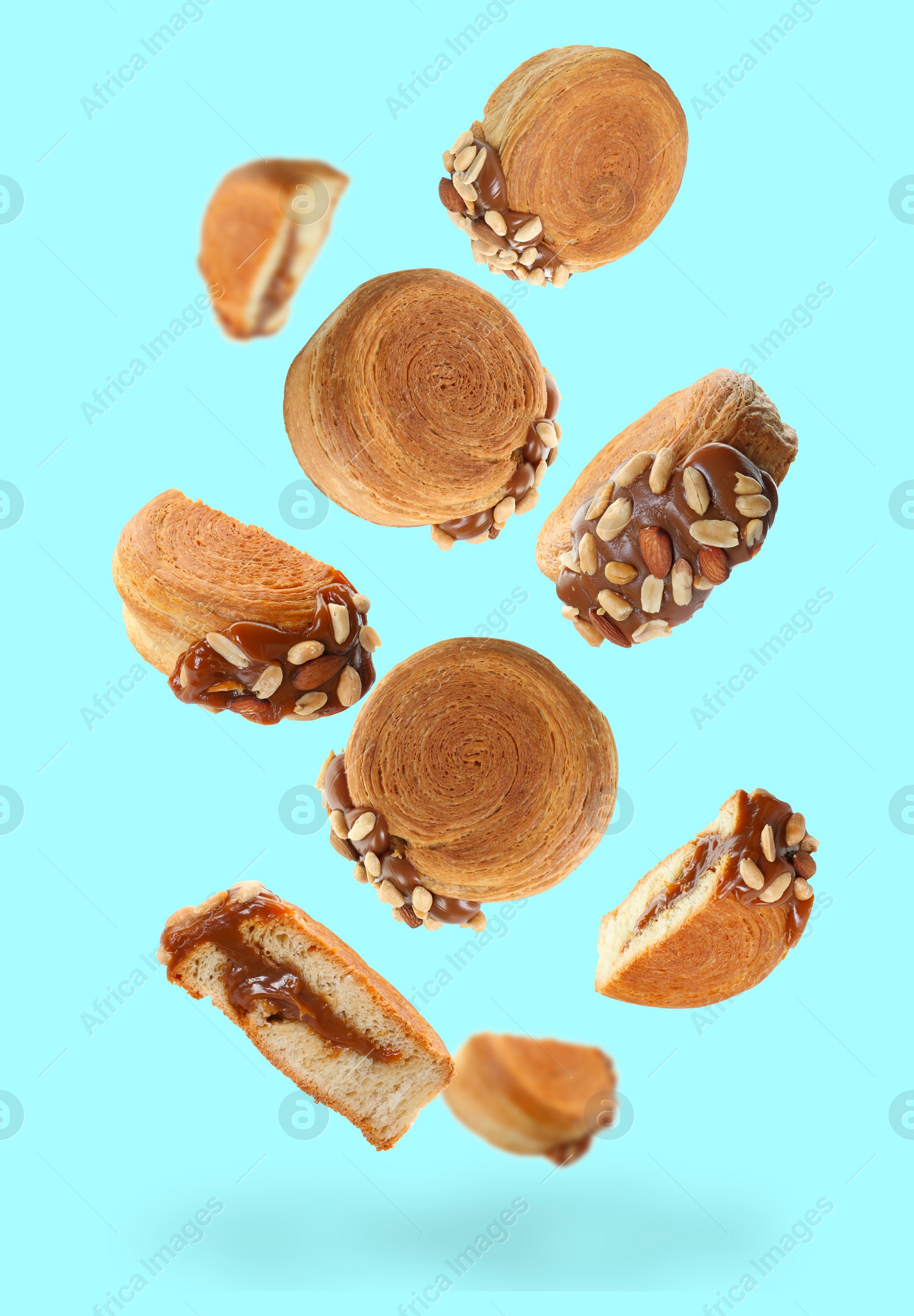 Image of Delicious round croissants in air on light blue background. Puff pastry