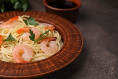 Tasty spaghetti with shrimps and parsley on brown textured table, closeup. Space for text