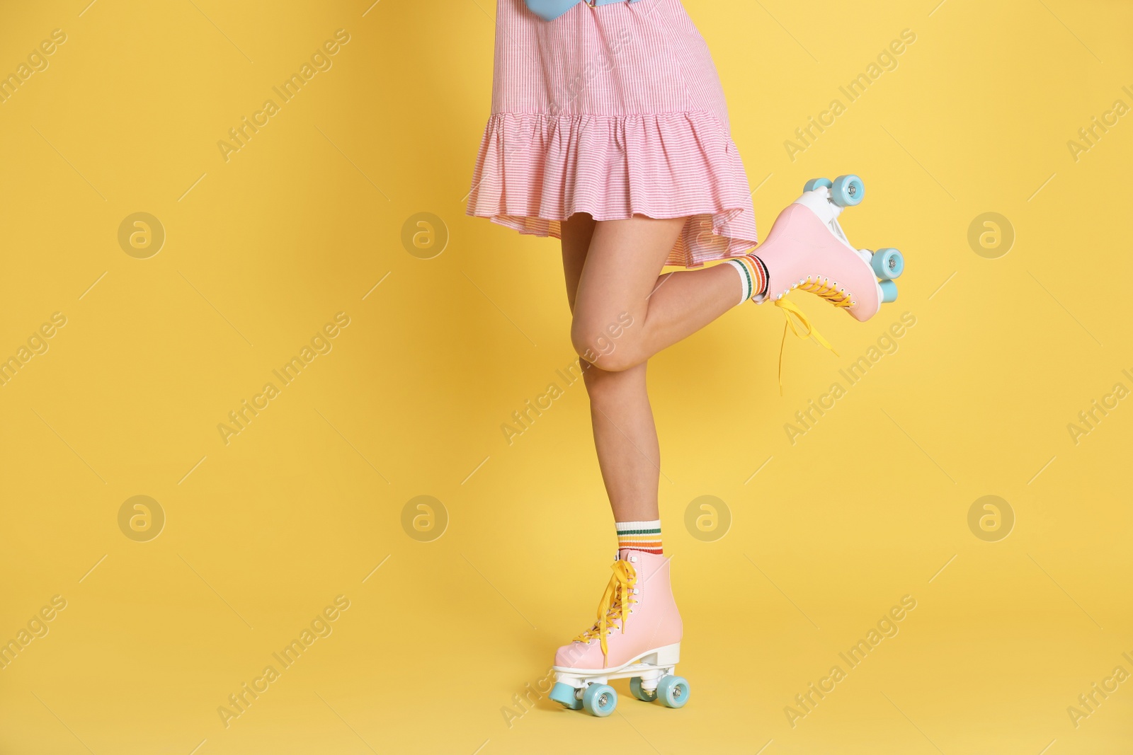 Photo of Young woman with retro roller skates on color background, closeup. Space for text