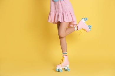 Photo of Young woman with retro roller skates on color background, closeup. Space for text
