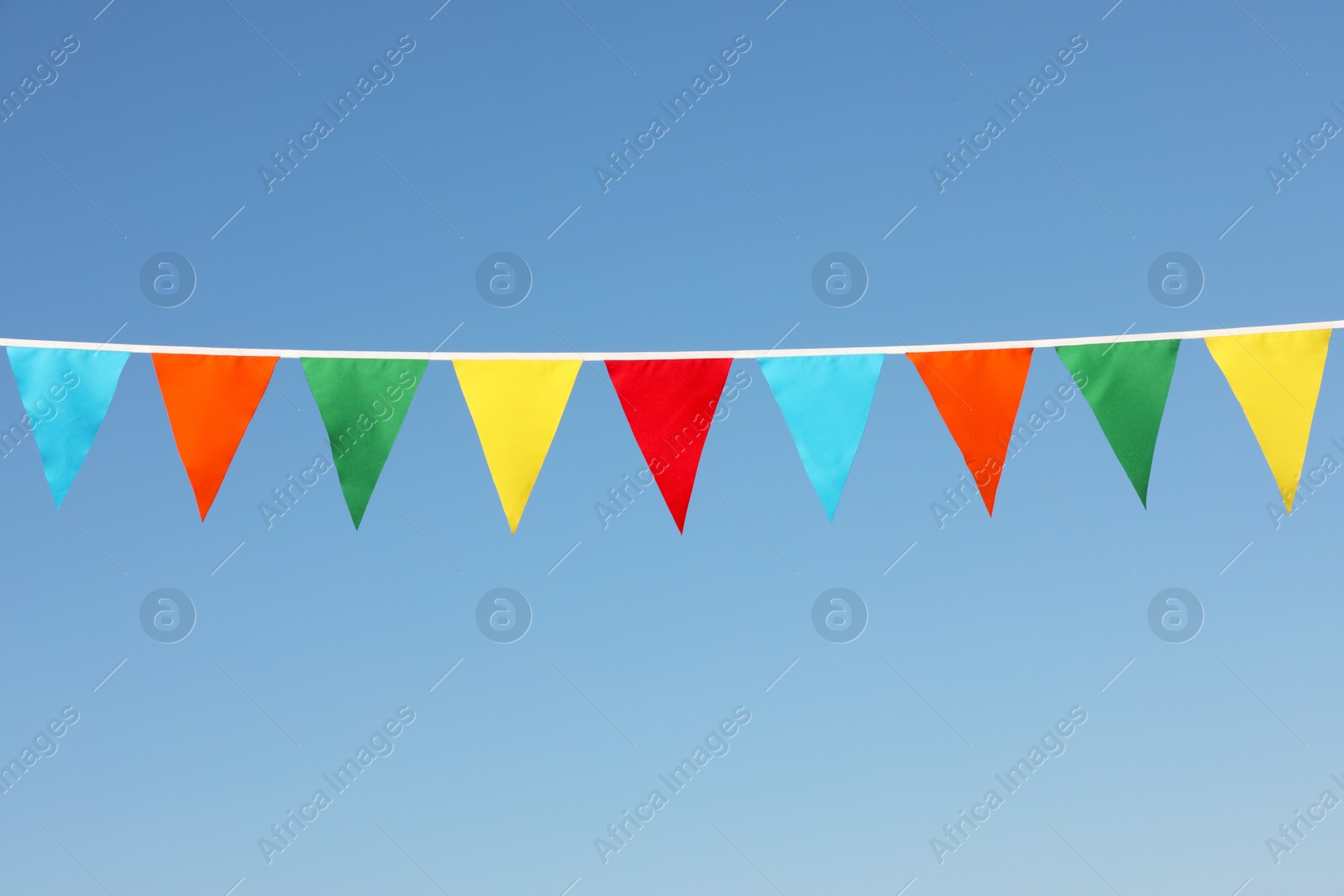 Photo of Bunting with colorful triangular flags against blue sky