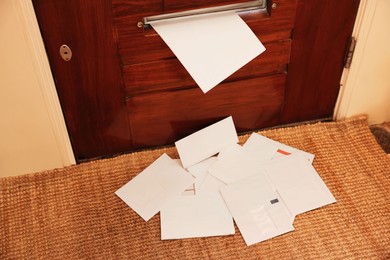 Photo of Wooden door with mail slot and many envelopes indoors