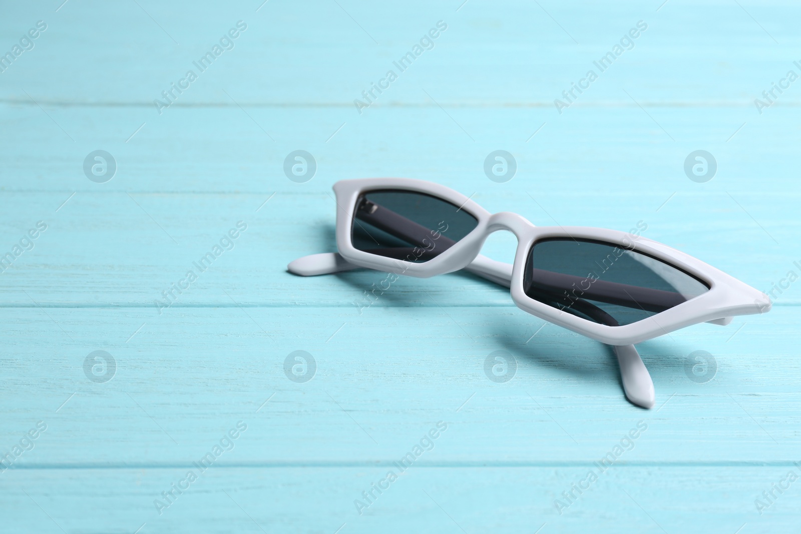 Photo of Stylish sunglasses on blue wooden background, space for text. Fashionable accessory