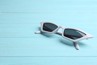 Stylish sunglasses on blue wooden background, space for text. Fashionable accessory